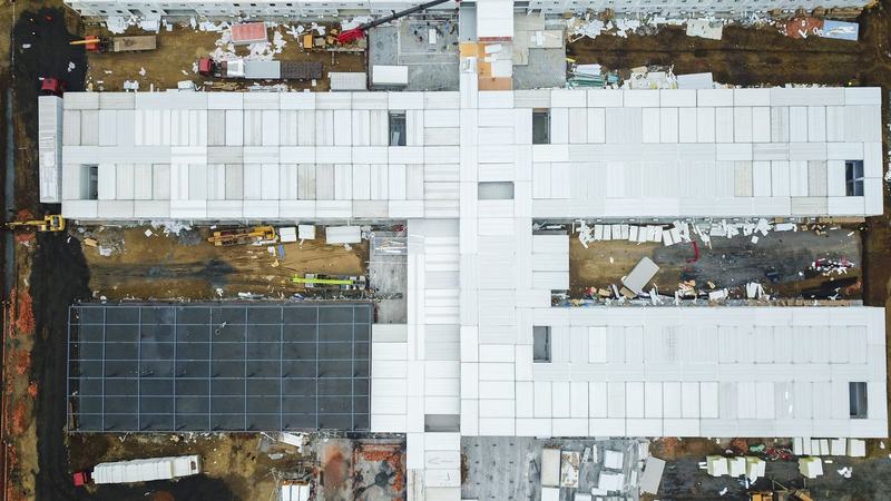 Aerial view of a large building under construction with cranes, deliveries and laydown areas