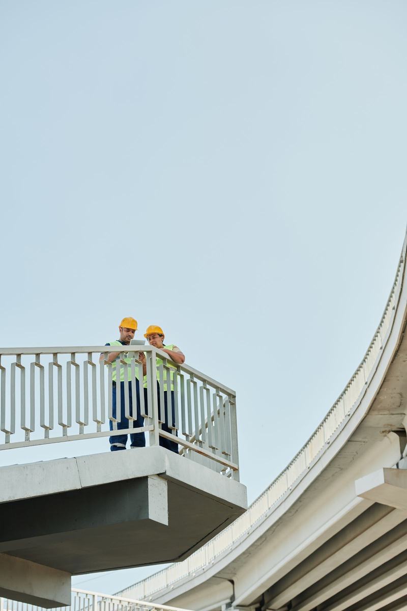 Two engineers in hard hats and hi-vis reviewing records on a completed footbridge deck