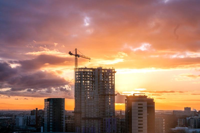 Tower cranes over a commercial construction skyline at sunset