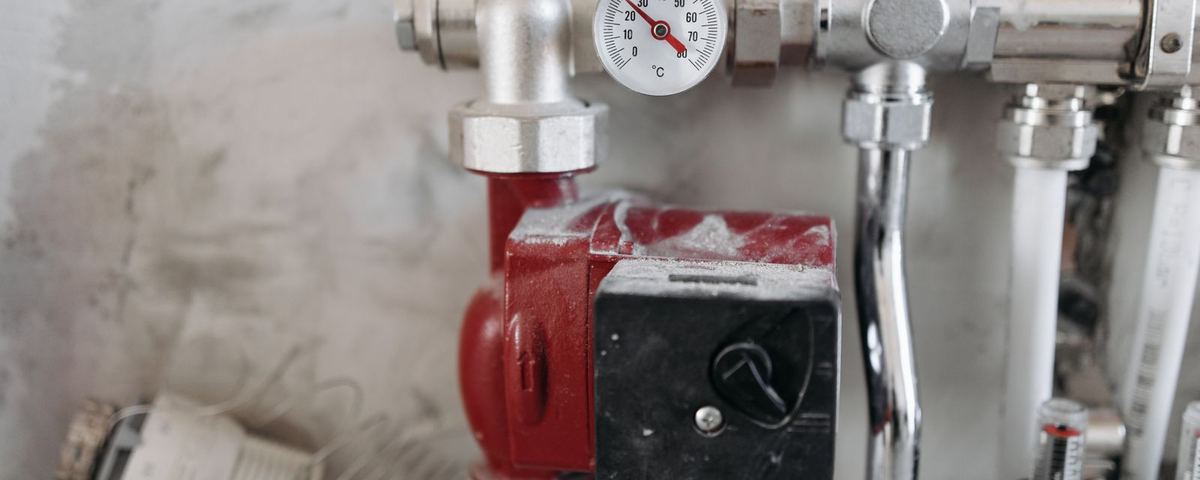 Circulating pump, valves and temperature gauge on a heating manifold awaiting commissioning