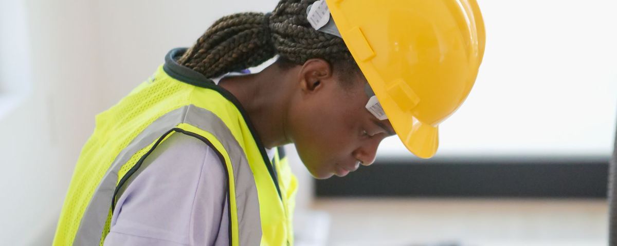Engineer in hard hat, safety glasses and hi-vis completing an inspection record on a clipboard