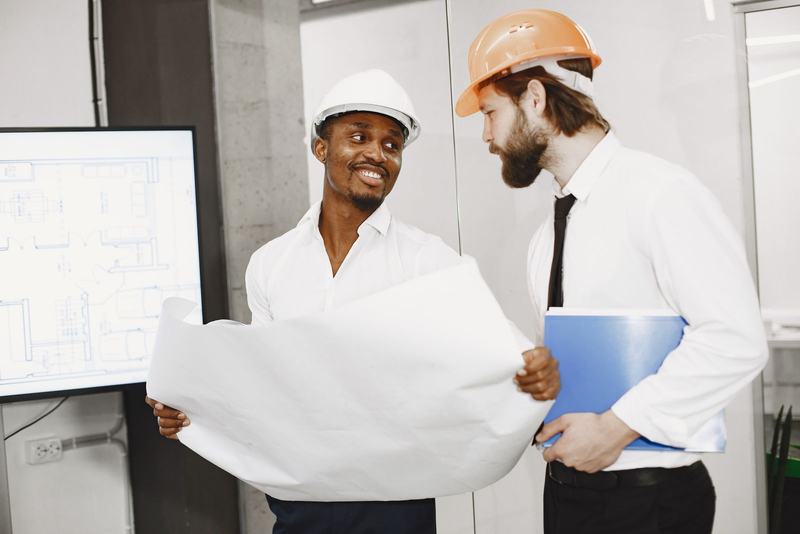 Two engineers in hard hats reviewing a drawing in a site office
