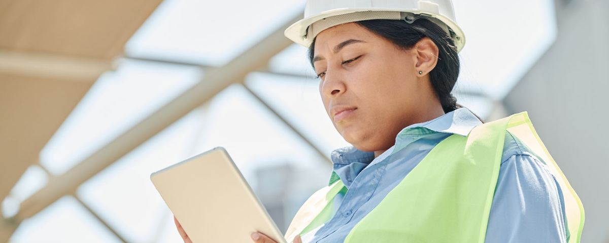 Site engineer in hard hat and hi-vis checking inspection records on a tablet